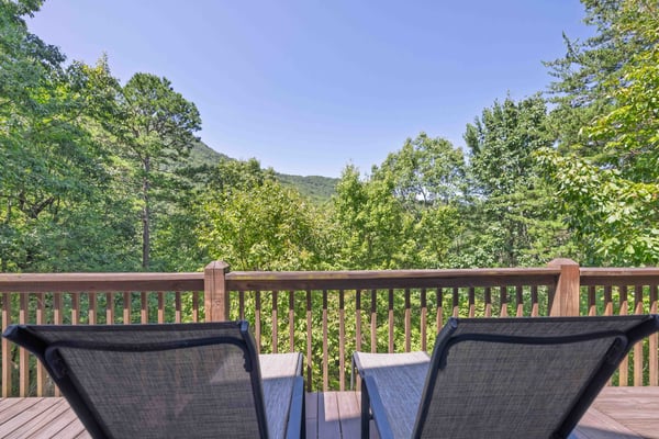 Two lounge chairs on a cabin deck overlooking Yonah Mountain through green forest, Cleveland, GA