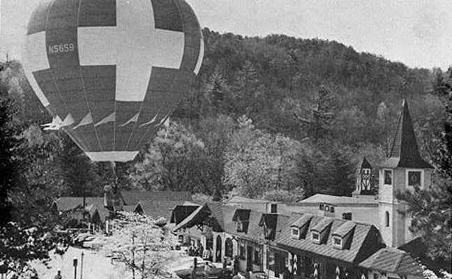 Black and white photograph of early Alpine Helen, Georgia, with a hot air balloon floating above the newly built Bavarian-style storefronts along Main Street